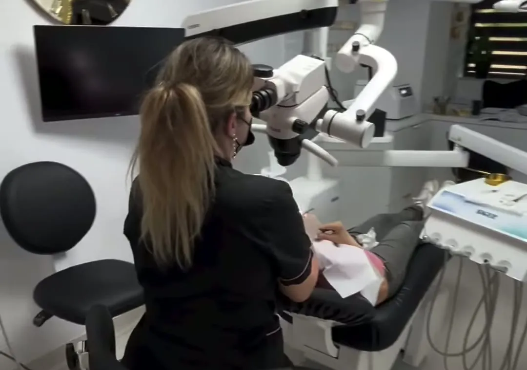 Medicul lucrează la microscopul dentar, în sala de tratament Andra Dent.