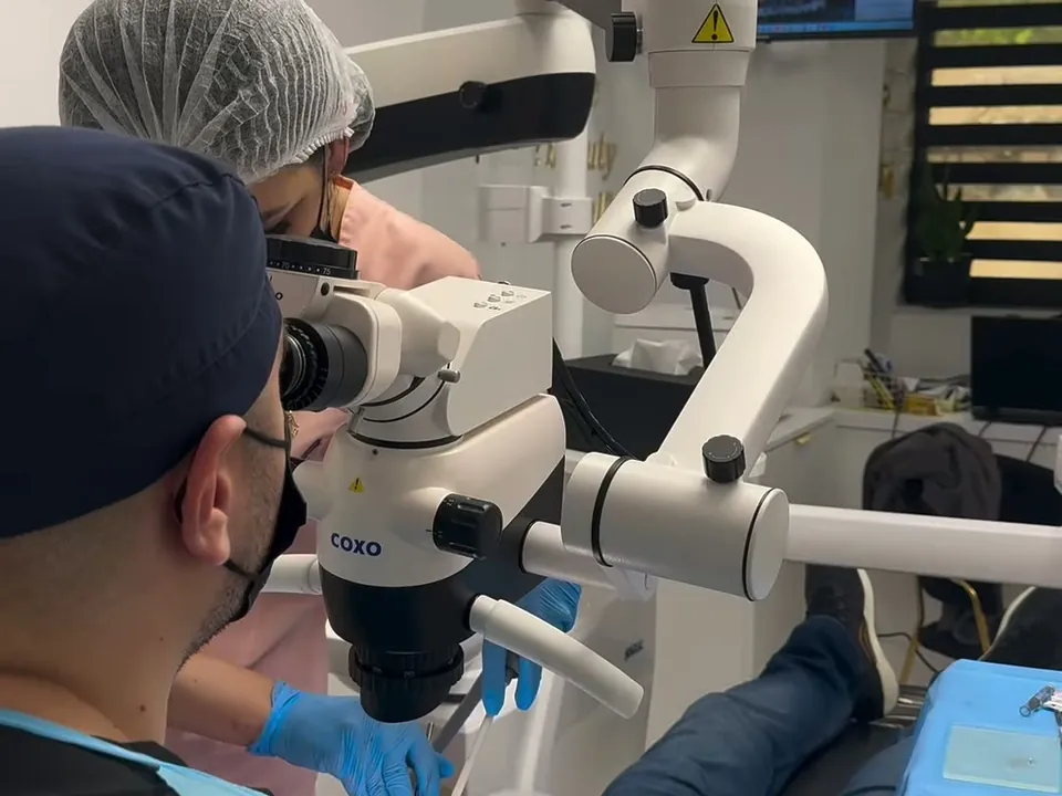 Medic Andra Dent lucrând la microscopul dentar COXO.